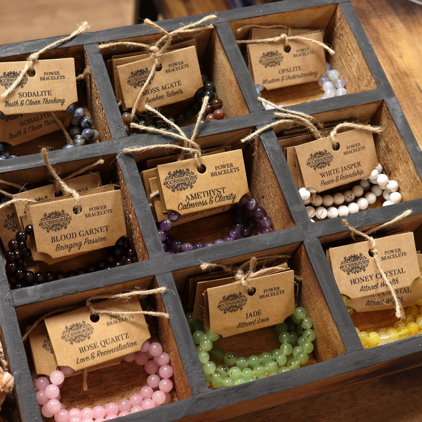 Wooden grid display of various Power bracelets with tags on a wooden surface.