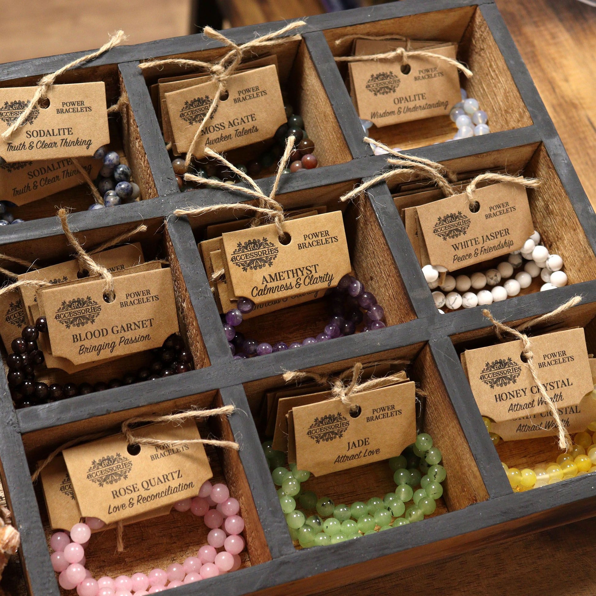 Wooden grid display of various Power bracelets with tags on a wooden surface.