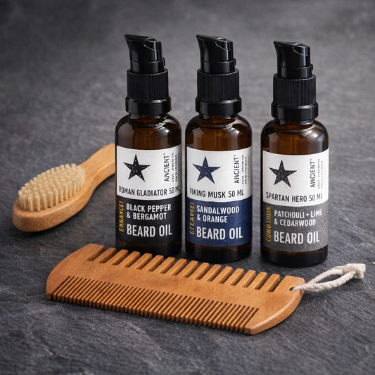 Three bottles of beard oil with a brush and comb on a dark surface