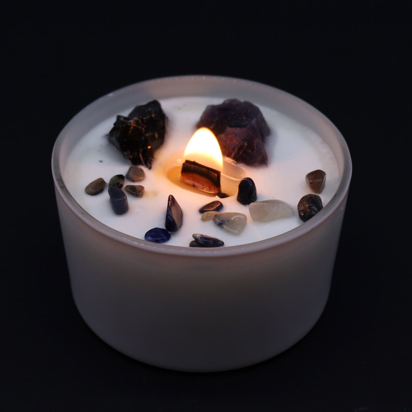 Candle with embedded crystals on a black background